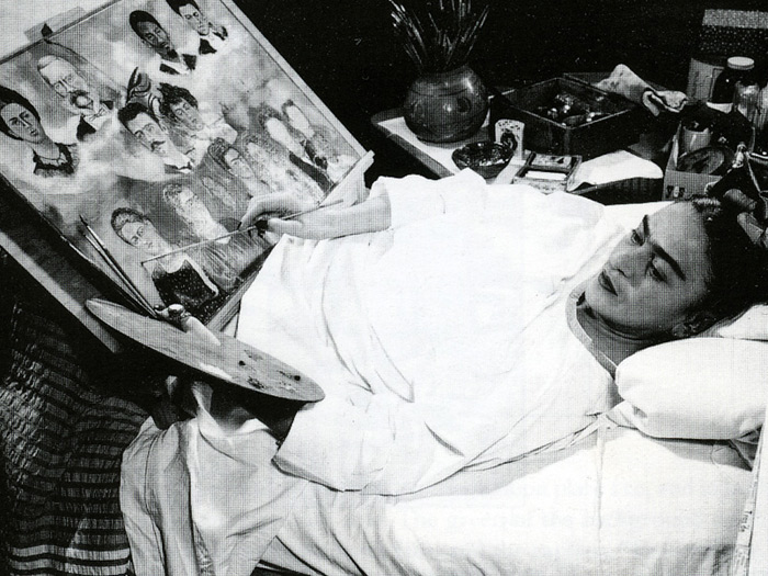 archiwalne zdjęcie (czarno-białe) Fridy Kahlo leżącej w łóżku i malującej jeden ze swoich obrazów